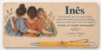 Placa impressa a cores com três amigas abraçadas, o nome Inês e esferográfica de bambu
