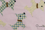 Detalle de toalla rosa con dibujos de perros tipo terrier con patrones geométricos.
