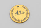 Medalha dourada com o nome Aita gravado dentro de uma orla de flores