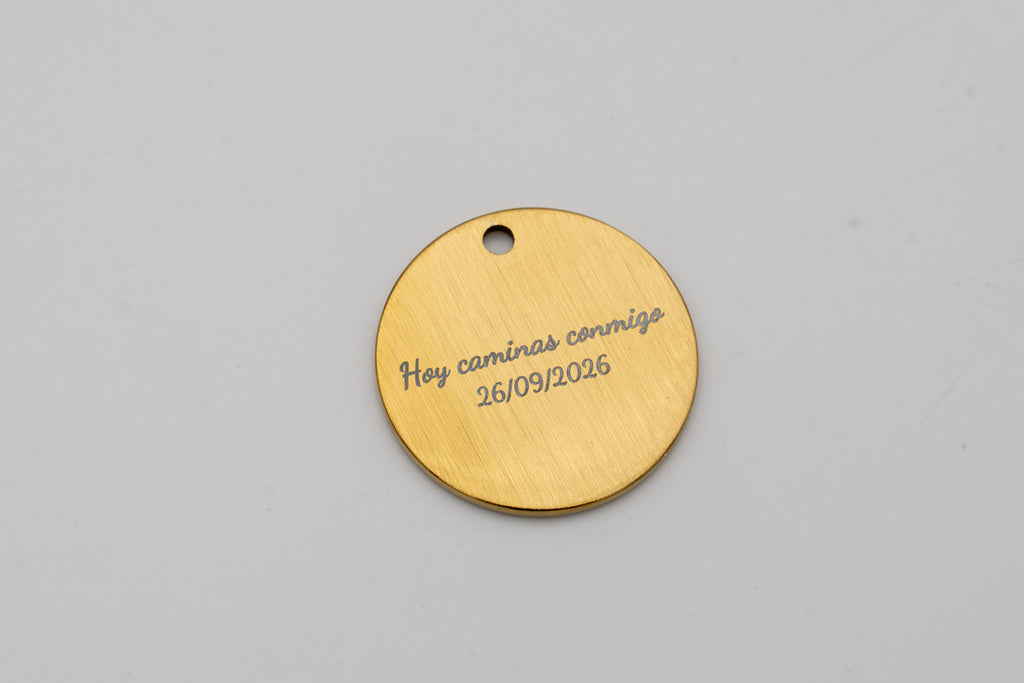 Medalha dourada escovada com a frase «Hoje caminhas comigo» e a data gravadas