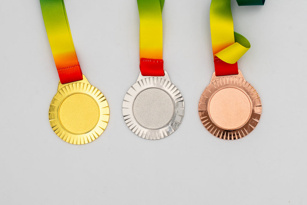 Medalhas com raios finos à volta do centro e fita vermelha e amarela.