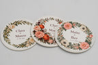 Conjunto de bases para copos redondas brancas com diferentes desenhos florais a cores.