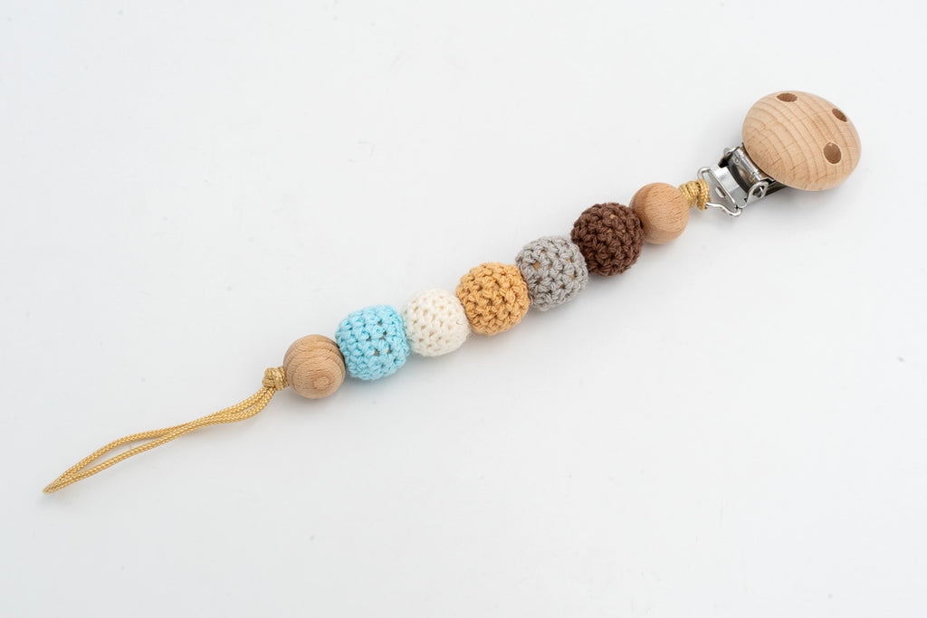 Prende-chupetas com contas revestidas a crochet em tons terra, branco e azul e clipe de madeira