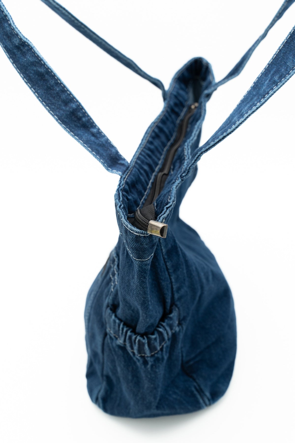 Perfil de uma mala de ganga que mostra o fecho de correr superior e um bolso lateral franzido.