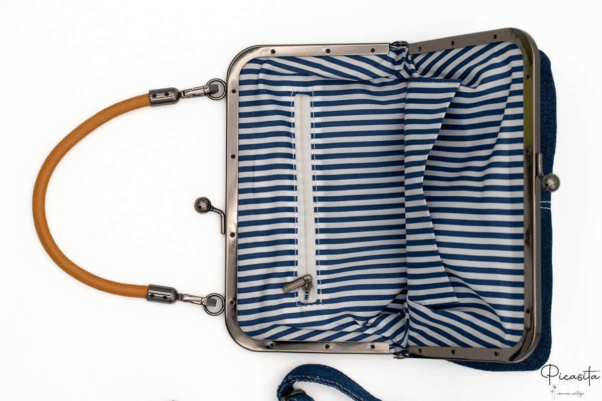 Interior de bolso con forro de rayas blancas y azules y bolsillo interno con cremallera.
