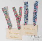 Dos carteles de madera personalizados para Nora y Aiala con diferentes cintas florales.