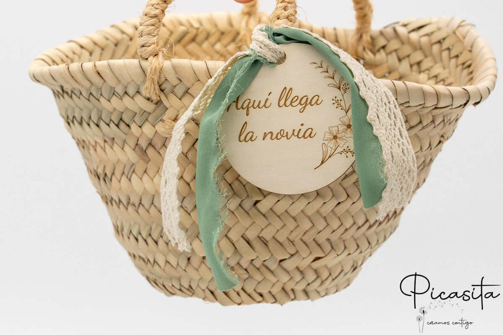 Cesto de hoja de palma con lazo verde y disco de madera decorativo para ceremonia.