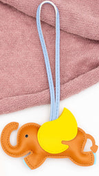 Elefante decorativo de polipiel naranja con ala amarilla y tira de sujeción azul.