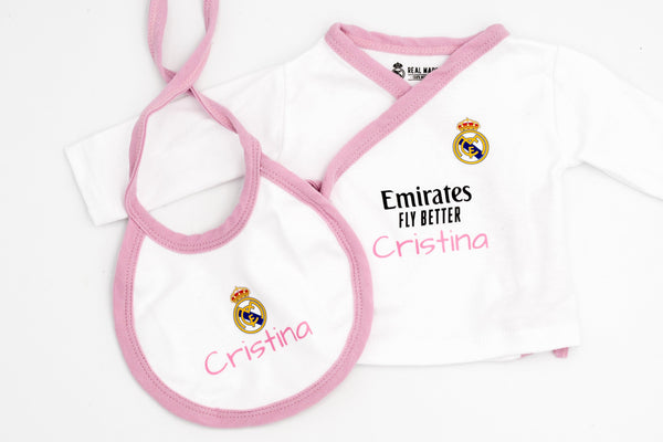 Camisola branca do Real Madrid com debrum rosa e o nome Cristina em rosa, junto ao babete