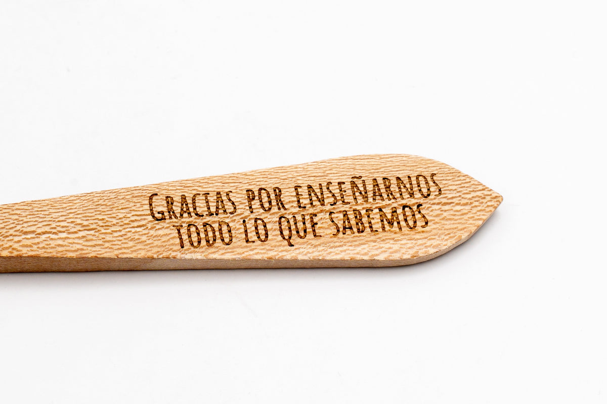 Texto conmemorativo grabado con precisión láser en la superficie plana del mango de madera.