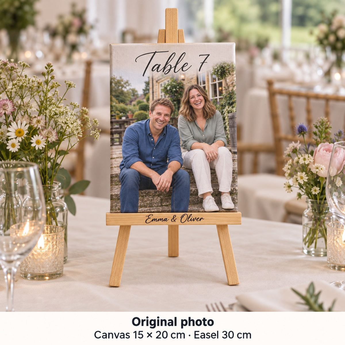 Tela de 15 × 20 cm com fotografia pré-casamento de Emma e Oliver e «Table 7», num cavalete sobre uma mesa do copo-d’água.