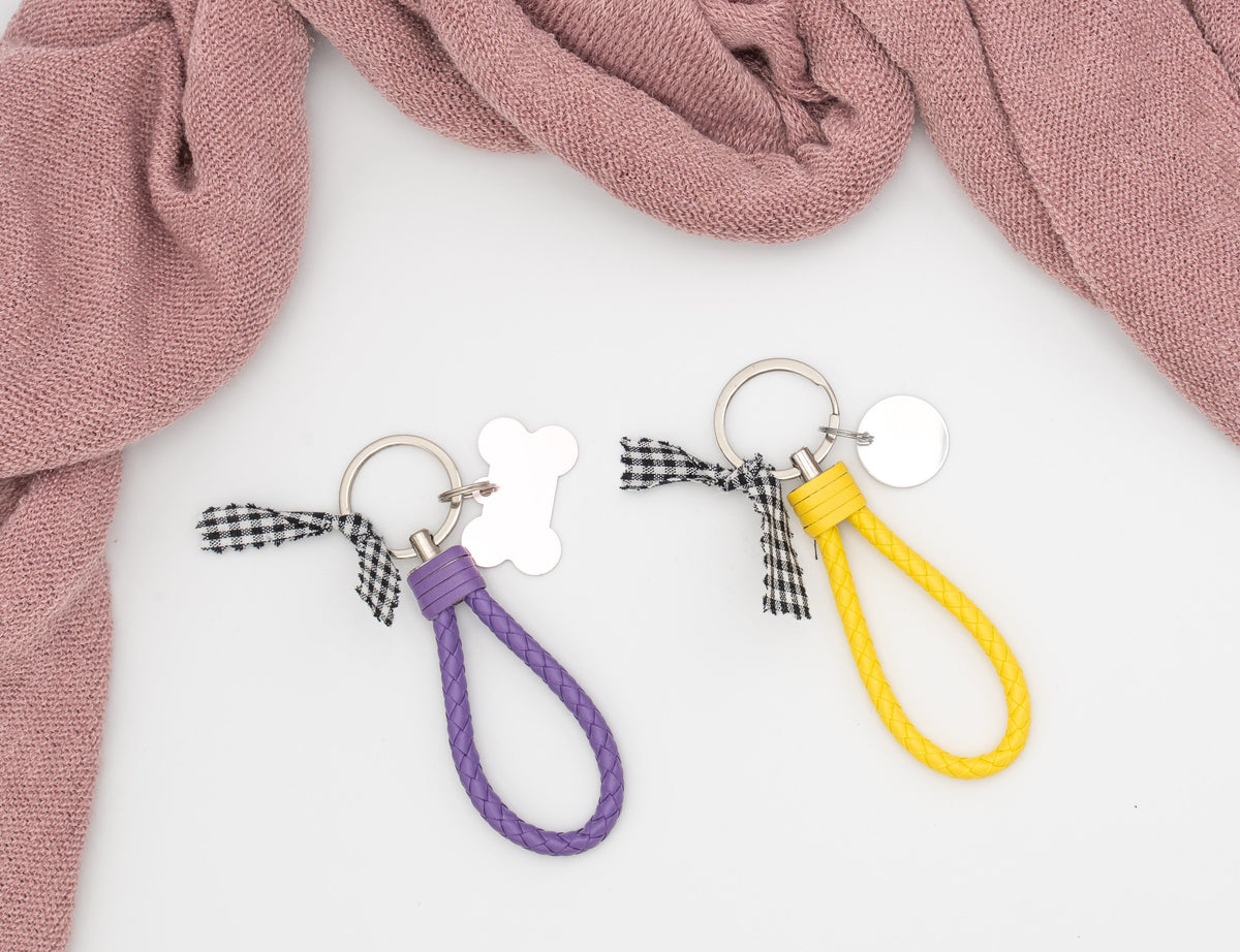 Porta-chaves entrançados de pele sintética em roxo e amarelo, com placas metálicas e laço vichy.