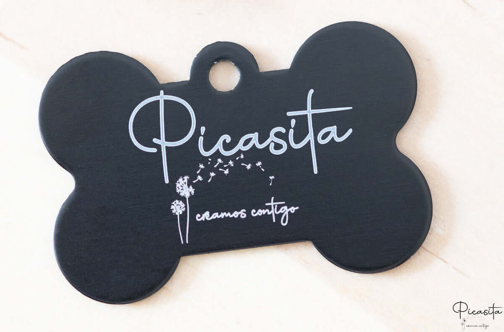 Placa de identificación negra en forma de hueso con grabado láser blanco de nombre y diseño floral.