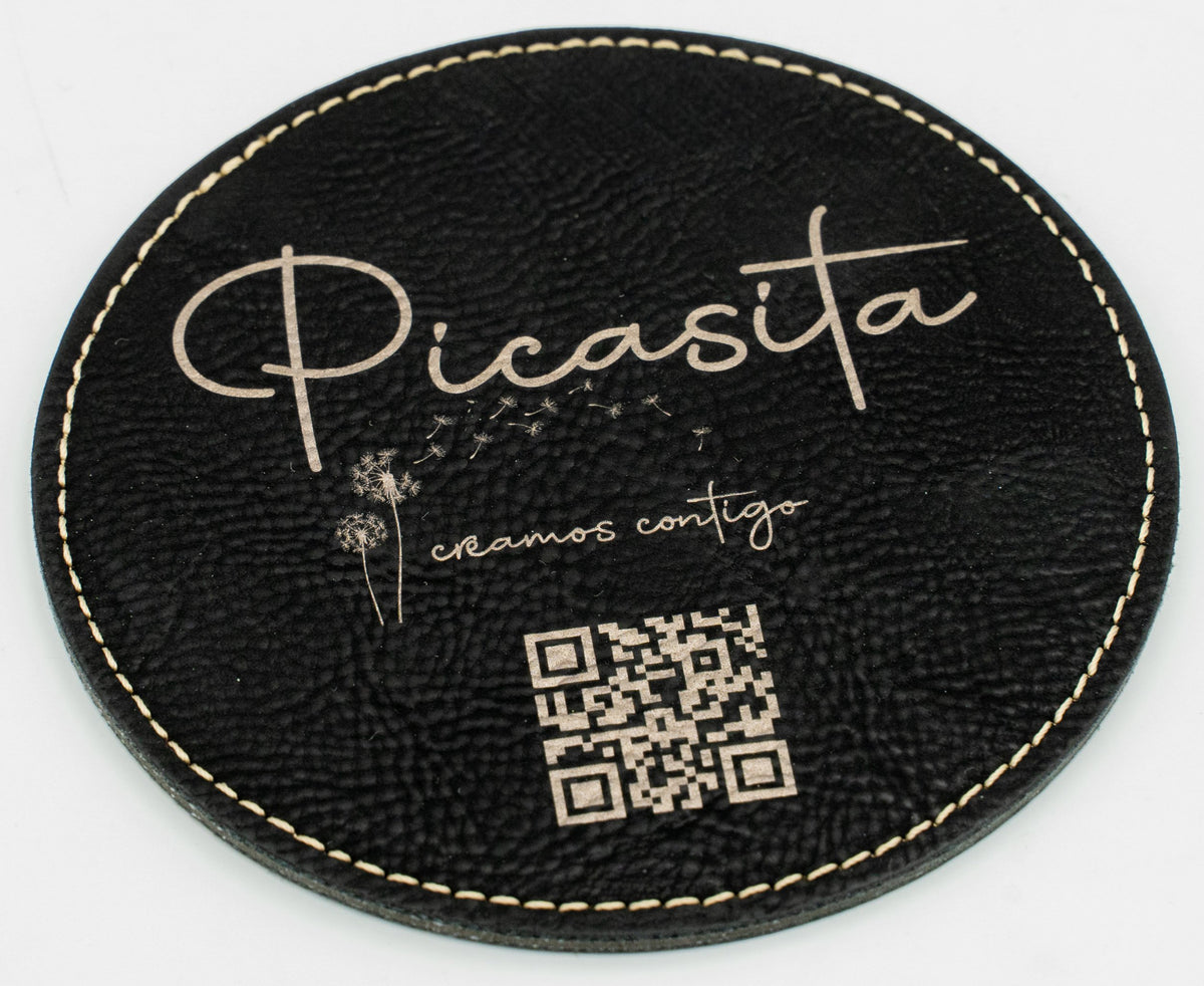 Base para copos redonda preta com marca Picasita e código QR em tom dourado.
