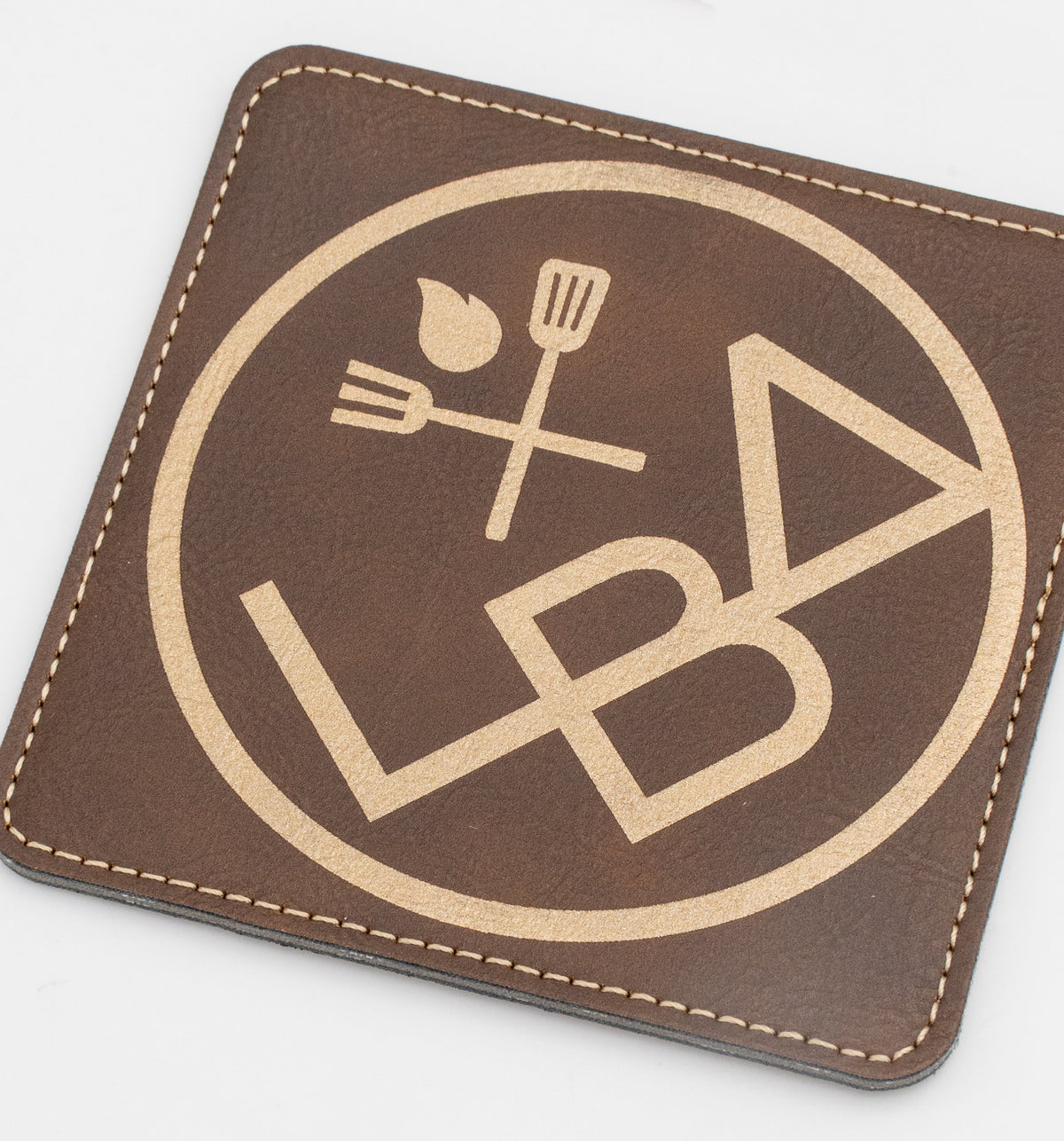 Base para copos quadrada castanha com logótipo de restauração em tom dourado.