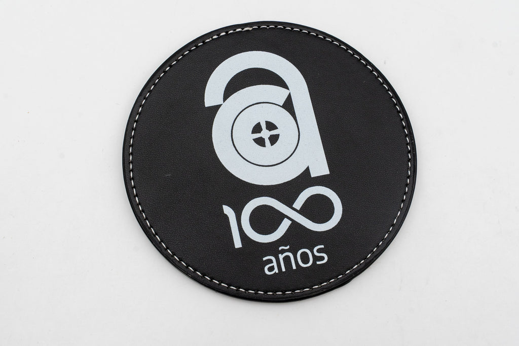 Base para copos redonda preta com logótipo comemorativo dos cem anos em branco.