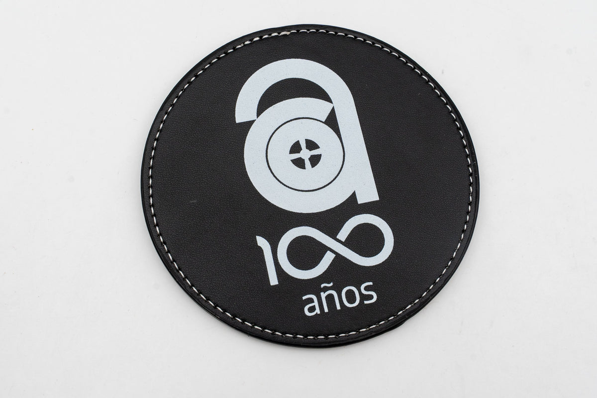 Base para copos redonda preta com logótipo comemorativo dos cem anos em branco.