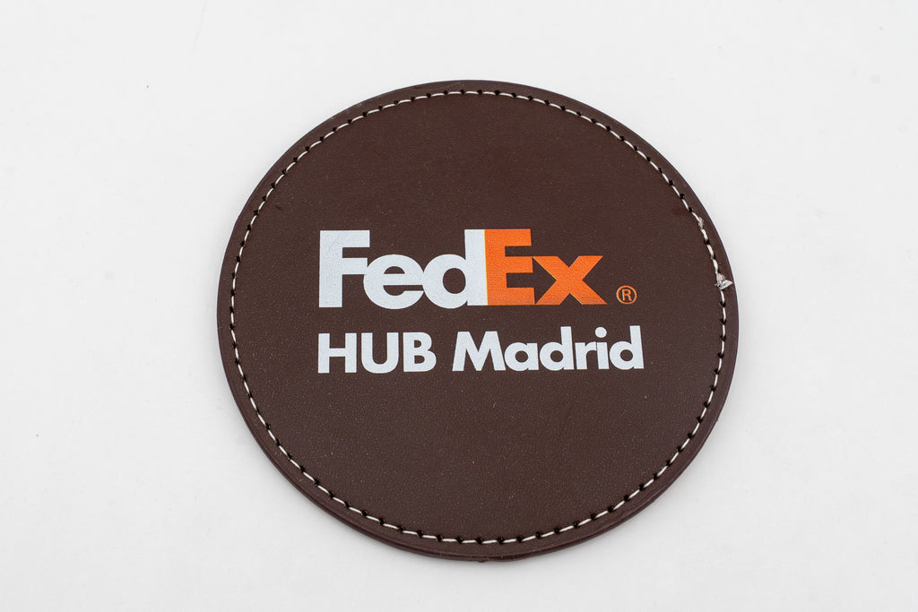 Base para copos redonda castanha com logótipo FedEx a cores.