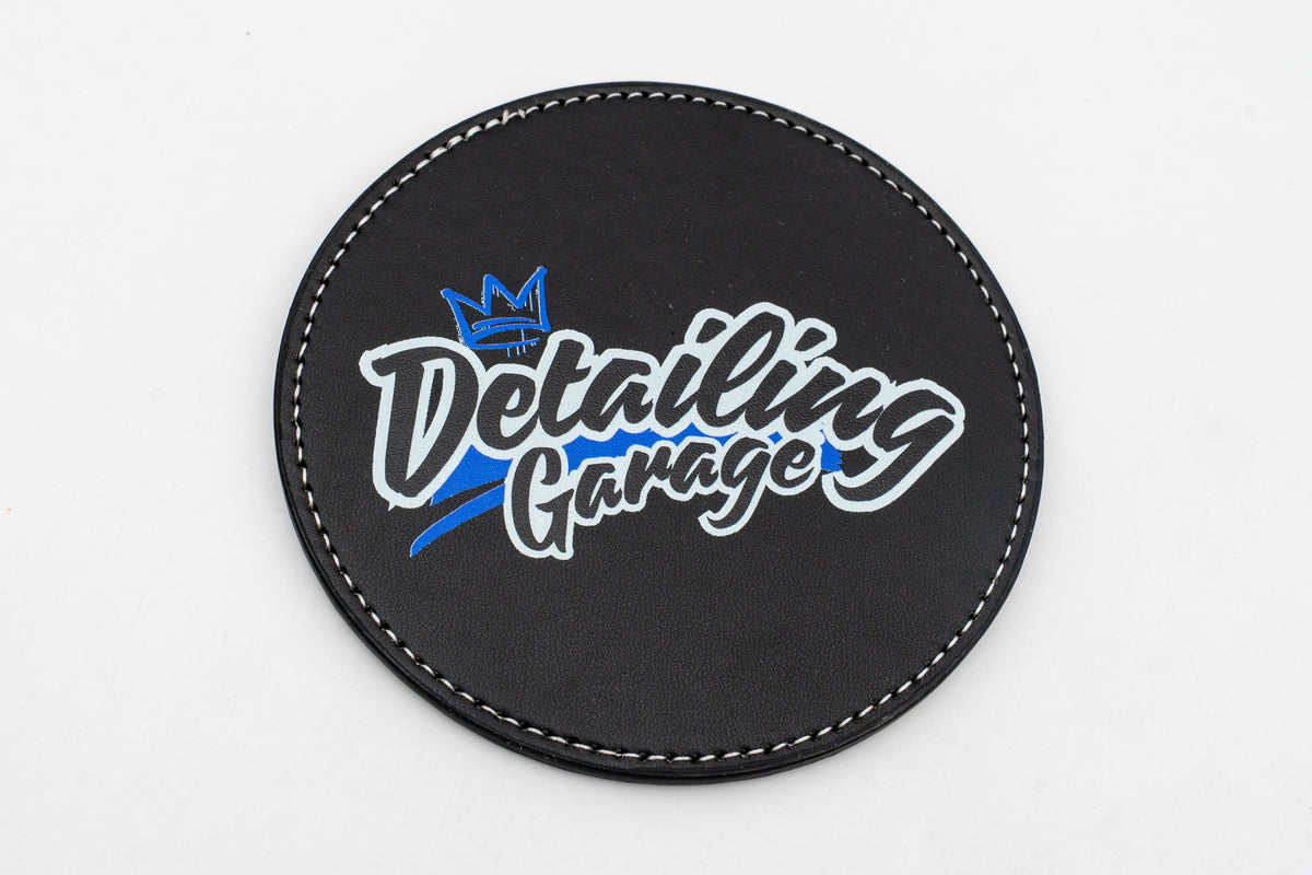 Base para copos redonda preta com logótipo Detailing Garage azul e amarelo.