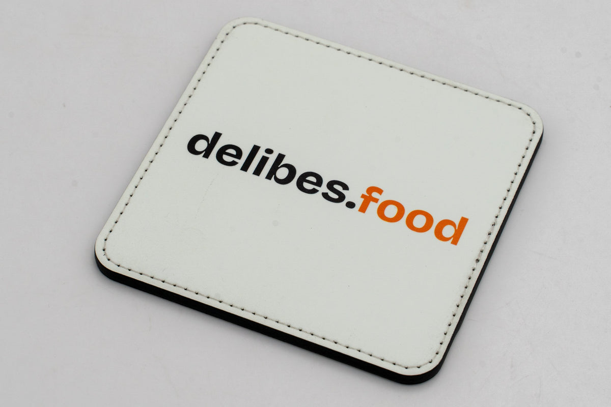 Base para copos quadrada branca com logótipo delibes.Food preto e laranja.