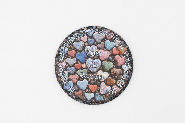 Base para copos redonda de ardósia com corações coloridos e nomes personalizados.