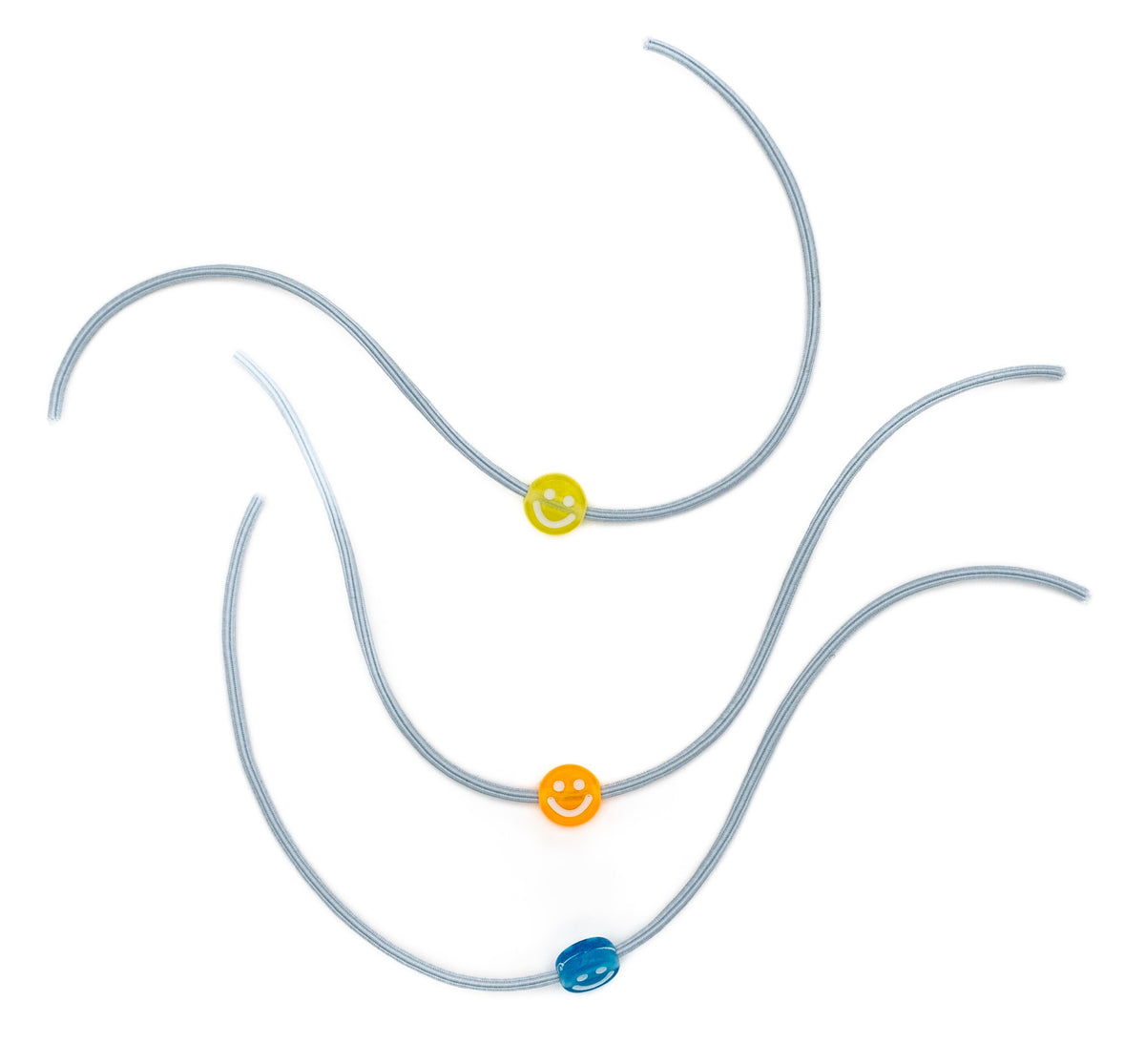 Três pulseiras elásticas cinzentas com contas em forma de sorriso nas cores amarela, laranja e azul.