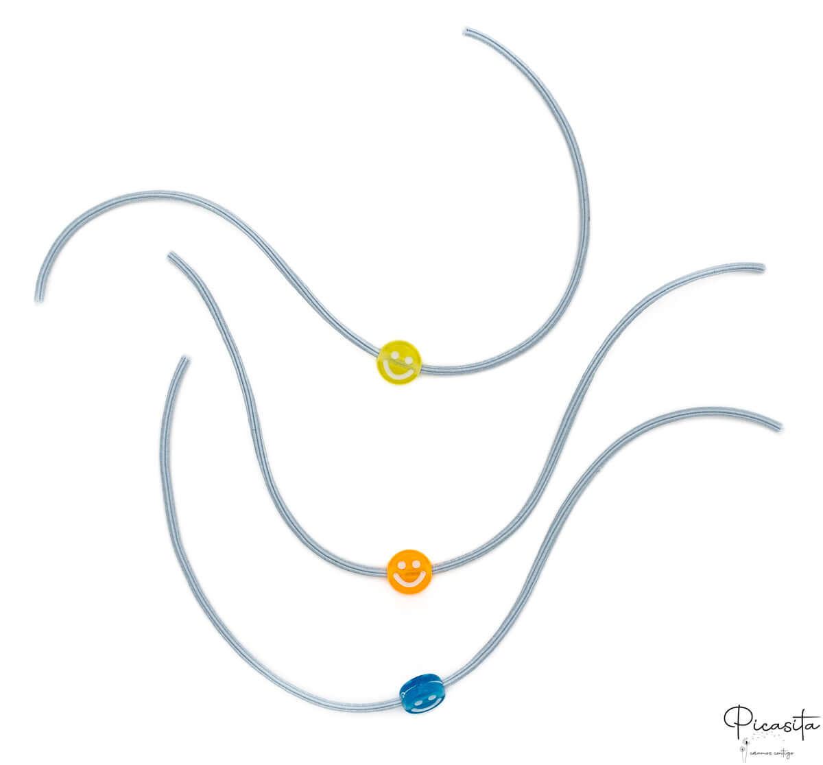 Tres pulseras elásticas grises con cuentas de sonrisas en amarillo, naranja y azul.