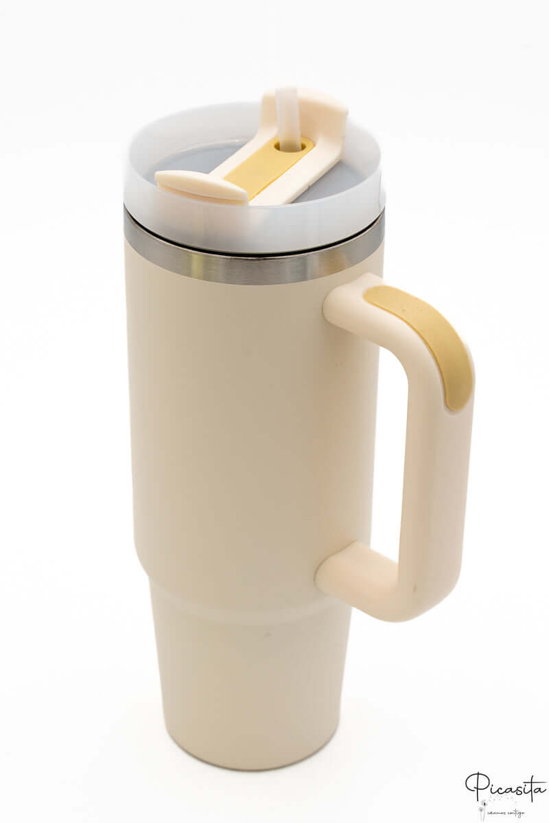 Termo color crema con asa y tapa con cierre en tono mostaza.