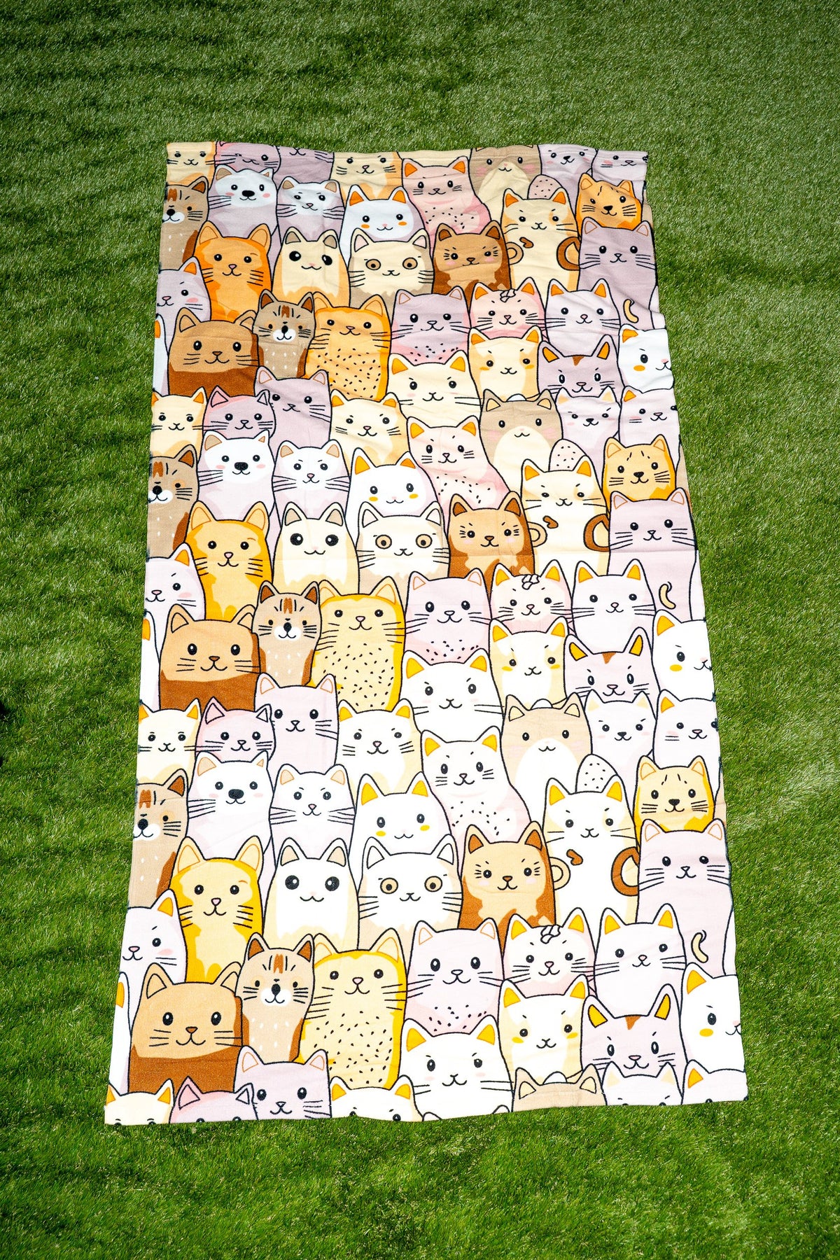 Toalha com desenho de gatos em tons terra, bege e branco sobre fundo claro.