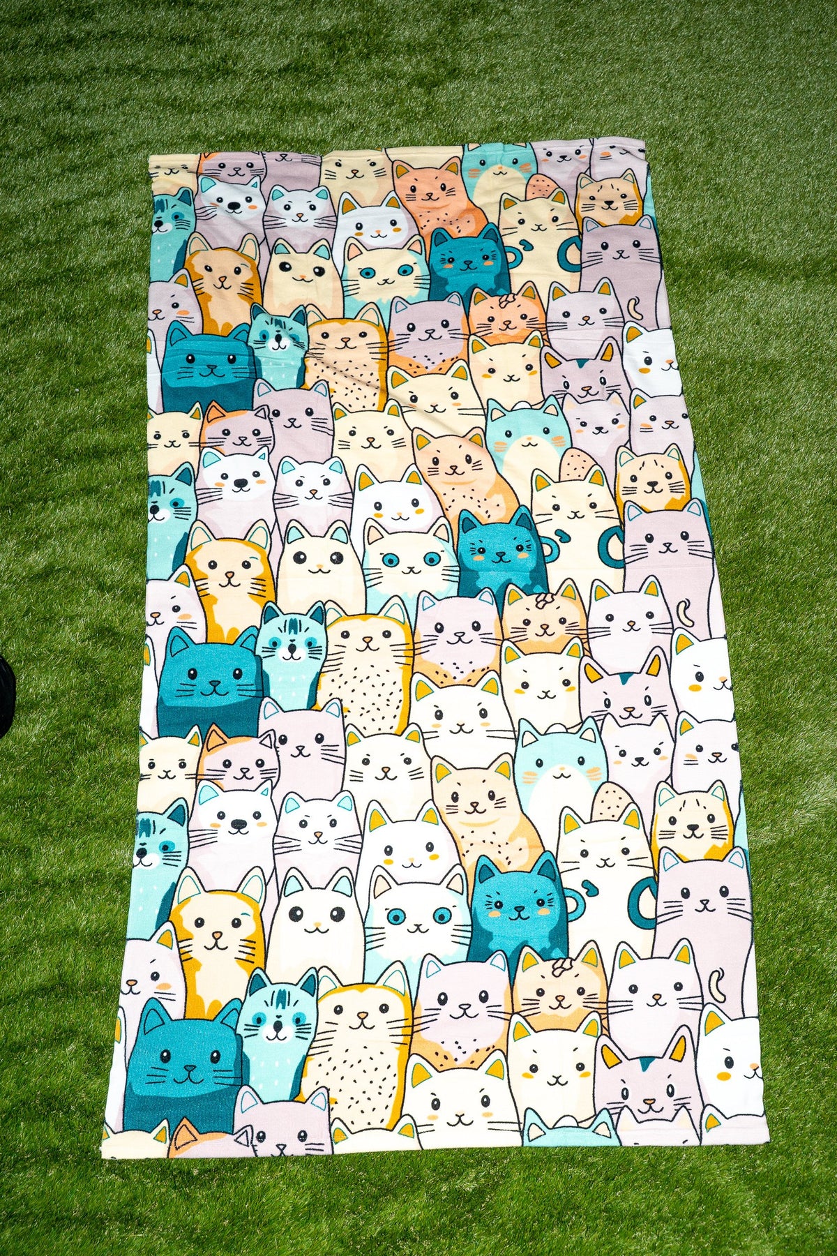 Toalha com padrão de gatinhos coloridos, incluindo tons turquesa e amarelo.