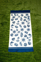 Toalla blanca con estampado náutico azul de anclas, conchas y timones.